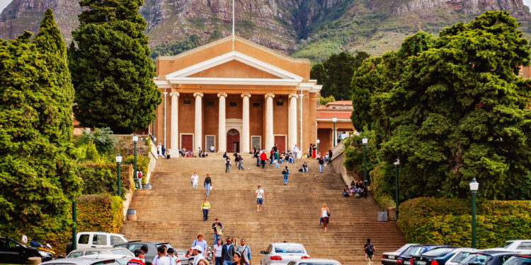 Cape Town, South Africa - April 17, 2007: The main building in the University of Cape Town in South Africa. Founded in 1829 it is the oldest institution of higher learning in the Country. Image shows several cars parked in front of the steps to the building. Many students can be seen walking away, or to the building; some just sit on the steps relaxing or chatting with friends. Photo shot in the afternoon sunlight; horizontal format.