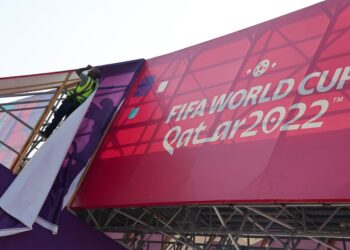 A worker fixes banners at Souq Waqif, which has been decorated ahead of the FIFA World Cup 2022 soccer tournament in Doha, Qatar November 11, 2022. REUTERS/Amr Abdallah Dalsh