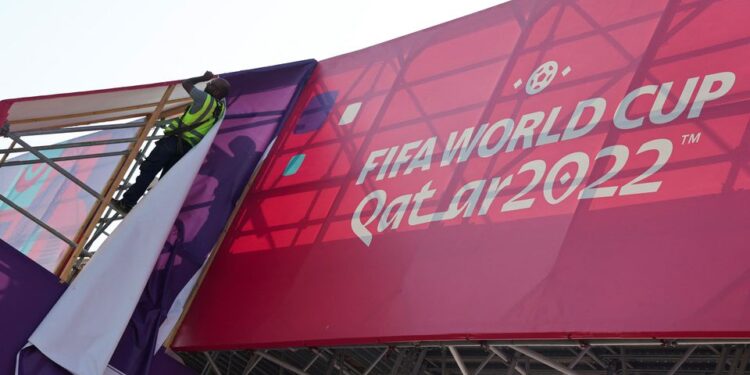 A worker fixes banners at Souq Waqif, which has been decorated ahead of the FIFA World Cup 2022 soccer tournament in Doha, Qatar November 11, 2022. REUTERS/Amr Abdallah Dalsh