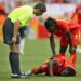 NUREMBERG, GERMANY - JUNE 22:  Michael Essien of Ghana lies injured under the gaze of referee Markus Merk and Razak Pimpong of Ghana during the FIFA World Cup Germany 2006 match between Ghana and USA played at the Stadium Nuernberg on June 22, 2006 in Nuremberg, Germany.  (Photo by Clive Brunskill/Getty Images)