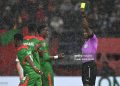 Ghanaian referee Daniel Nii Ayi Laryea (R) gives a yellow card to Burkina Faso's midfielder #20 Gustavo Sangare during the Africa Cup of Nations (CAN) Group E football match between Algeria and Burkino Faso at Moulay Hassan Stadium in Rabat on December 28, 2025. (Photo by Paul ELLIS / AFP via Getty Images)