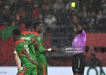 Ghanaian referee Daniel Nii Ayi Laryea (R) gives a yellow card to Burkina Faso's midfielder #20 Gustavo Sangare during the Africa Cup of Nations (CAN) Group E football match between Algeria and Burkino Faso at Moulay Hassan Stadium in Rabat on December 28, 2025. (Photo by Paul ELLIS / AFP via Getty Images)