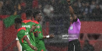 Ghanaian referee Daniel Nii Ayi Laryea (R) gives a yellow card to Burkina Faso's midfielder #20 Gustavo Sangare during the Africa Cup of Nations (CAN) Group E football match between Algeria and Burkino Faso at Moulay Hassan Stadium in Rabat on December 28, 2025. (Photo by Paul ELLIS / AFP via Getty Images)