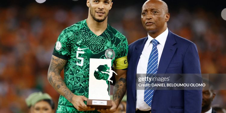 TOPSHOT - Nigeria's defender #5 William Troost-Ekong holds the Golden Ball award while standing next to President of the Confederation of African Football (CAF) Patrice Motsepe (R) during prize giving ceremony following the Africa Cup of Nations (CAN) 2024 final football match between Ivory Coast and Nigeria at Alassane Ouattara Olympic Stadium in Ebimpe, Abidjan on February 11, 2024. (Photo by Daniel BELOUMOU OLOMO / AFP) (Photo by DANIEL BELOUMOU OLOMO/AFP via Getty Images)