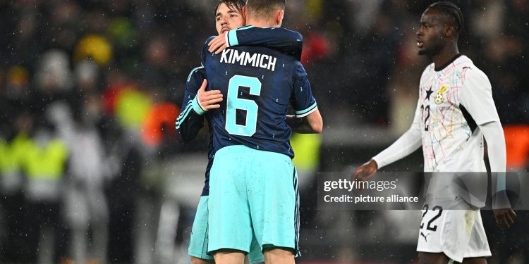 30 March 2026, Baden-Württemberg, Stuttgart: Soccer, men, international matches, Germany - Ghana, MHP Arena. Lennart Karl (back, Germany) is happy after the game with Joshua Kimmich (Germany), Kamaldeen Sulemana (Ghana) runs past the two. Photo: Tom Weller/dpa - IMPORTANT NOTE: In accordance with the regulations of the DFL German Football League and the DFB German Football Association, it is prohibited to utilize or have utilized photographs taken in the stadium and/or of the match in the form of sequential images and/or video-like photo series. (Photo by Tom Weller/picture alliance via Getty Images)