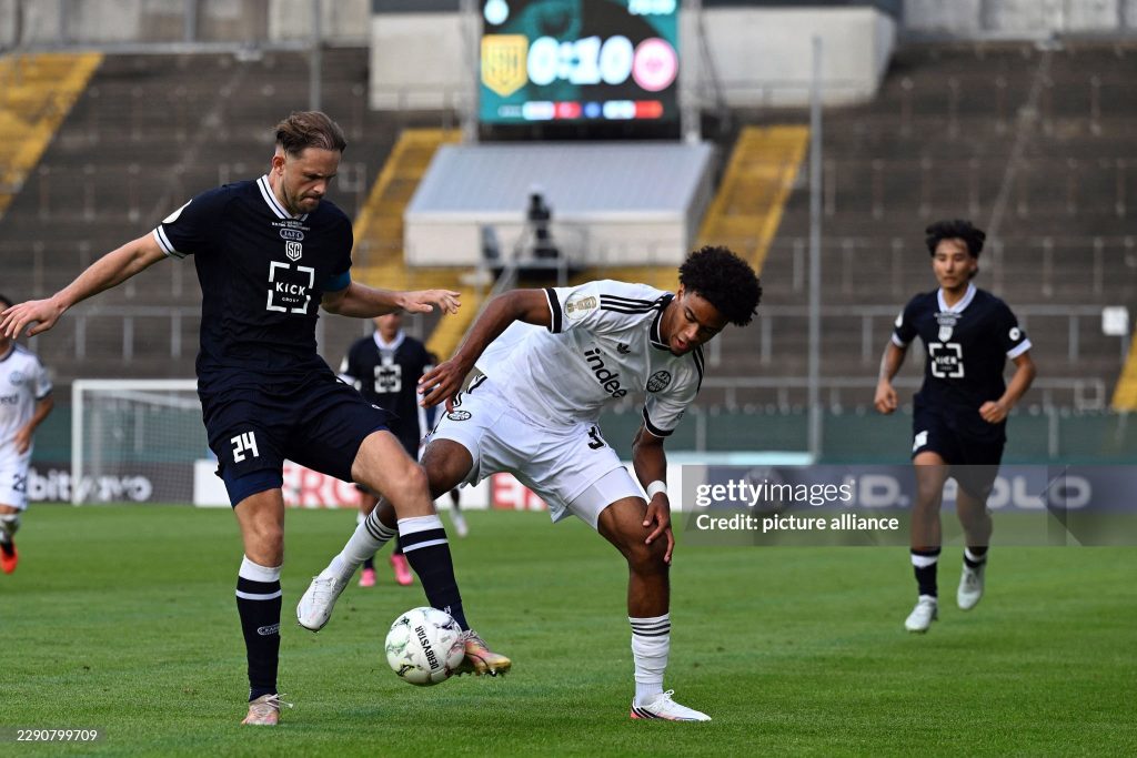 21 August 2026, North Rhine-Westphalia, Krefeld: Soccer, Men: DFB Cup, SC St. Tönis 11/20 vs. Eintracht Frankfurt, First Round, Grotenburg Stadium; Bilal Brusdeilins (left, Tönis) and Malik Pimpong (Eintracht Frankfurt) battle for the ball. Photo: Federico Gambarini/dpa - IMPORTANT NOTICE: In accordance with the regulations of the Bundesliga and the DFB (German Football Association), it is prohibited to use or allow the use of photographs taken in the stadium and/or during the game in the form of sequential images and/or video-like photo series. (Photo by Federico Gambarini/picture alliance via Getty Images)