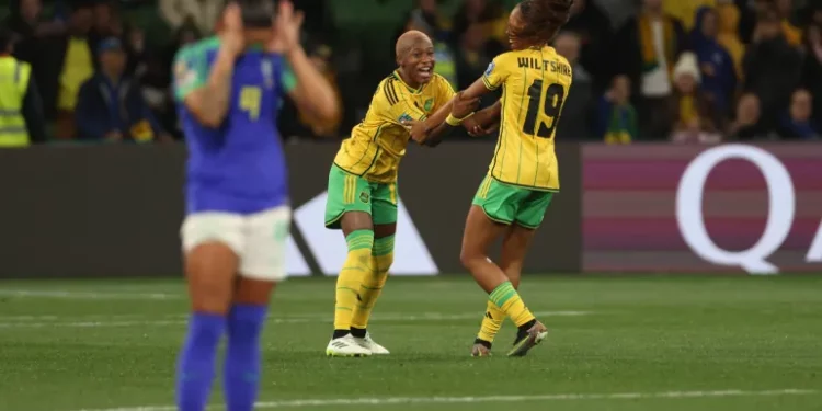 Jamaica's Deneisha Blackwood, centre, celebrates with her teammate Jamaica's Tiernny Wiltshire as the Reggae Girlz make it to the knockout round for the first time [Hamish Blair/AP Photo]