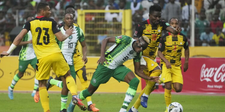 Nigeria's Victor Osimhen, centre is challenged by Ghana’s Daniel Amartey, right, during their 2022 Qatar World Cup qualifying playoff second leg at Moshood Abiola Stadium in Abuja, Nigeria, Tuesday, March. 29, 2022. Ghana became the first team from Africa to qualify for the World Cup in Qatar after a 1-1 draw with Nigeria in the second leg of their playoff on Tuesday to advance on away goals. (AP Photo/Sunday Alamba)